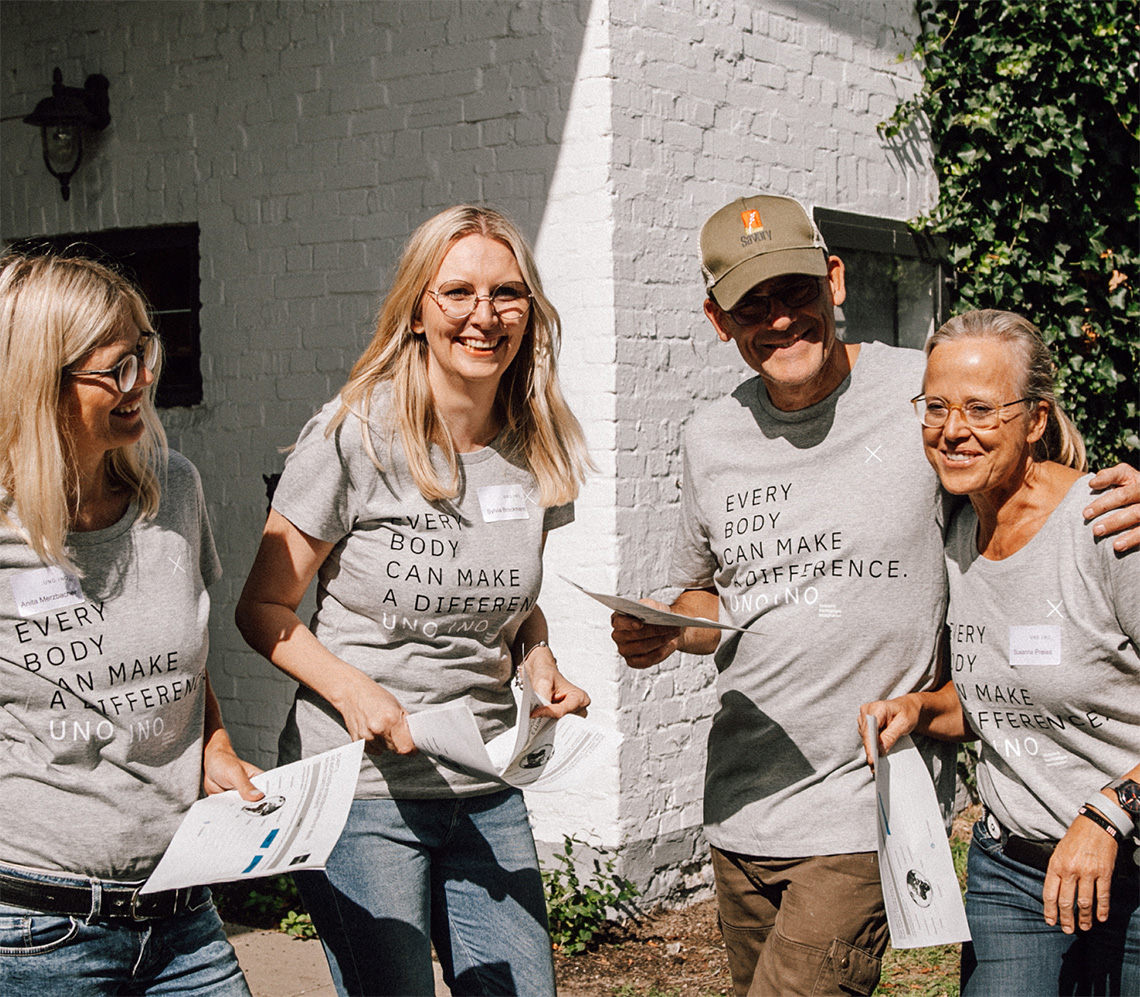 Auf dem Bild sieht man herzlich lachende Menschen in T-Shirts der Marke UNO INO. Die T-Shirts sind mit dem Claim Everybody can make a difference bedruckt.